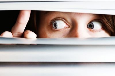 Девушка смотрит через жалюзи